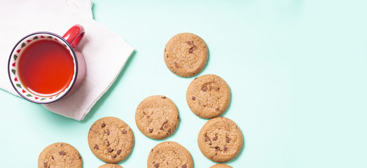 red Christmas mug with Christmas trees with black tea and homemade cookies on a napkin on a light background, close-up with copy space