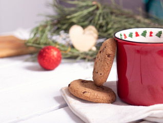 red christmas mug with tea, homemade cookies and fir branches on a light background