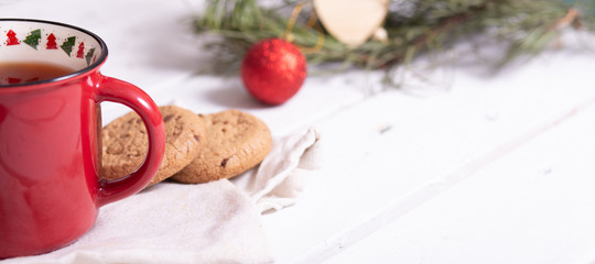 red christmas mug with tea, homemade cookies and fir branches on a light background, banner