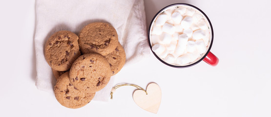 Red mug with cocoa and marshmallows and homemade cookies with chocolate, wooden heart - Christmas tree toy on a light background