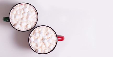 two mugs green and red with cocoa and marshmallows on a light background