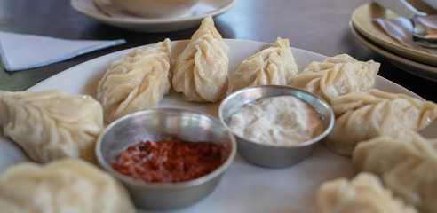 A dish of the tibetan fried momo with a sauce. Momo is a dish of dough with a filling.