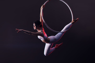 Young woman performing acrobatic element on aerial ring indoors - obrazy, fototapety, plakaty