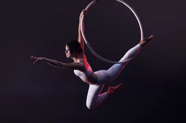 Foto op Plexiglas Young woman performing acrobatic element on aerial ring indoors © New Africa