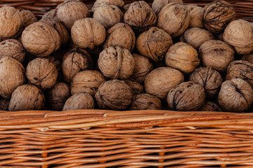 Wicker basket full of whole walnuts. Detailed closeup just edge of the basket visible.