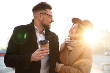 Lovely couple with cup of coffee on city street in morning