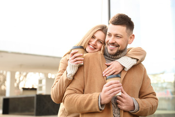 Lovely couple with cups of coffee on city street in morning