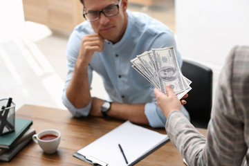 Woman offering bribe money to man at table, closeup