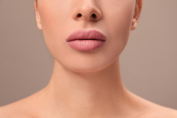 Woman with pink lipstick on brown background, closeup