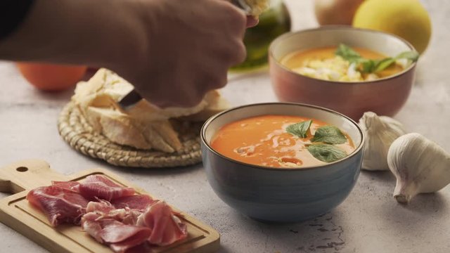 Serving salmorejo and egg in a bowl, with various ingredients around. Salmorejo is a tomato soup