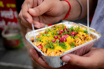 hands holding bowl of bhel puri