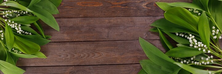 Fototapeta premium The decor of the flowers of lily of the valley on the background of vintage wooden boards. Vintage background with frame of flowers and place under the text. Flat lay.