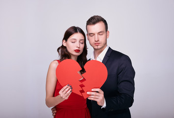 Fototapeta na wymiar Elegant couple in stylish clothes with a broken red heart on a white background.