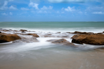 Long exposure photography. Silk effect in water. Marine rocks bathed in foam that forms a mist. Landscape at the edge of the sea.