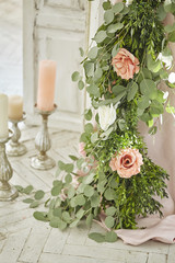 Flower arrangement of roses and eucalyptus trees, next to which are candlesticks. 