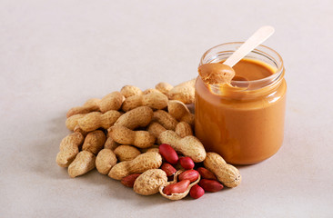 Peanut butter in a jar and peanuts in shells near