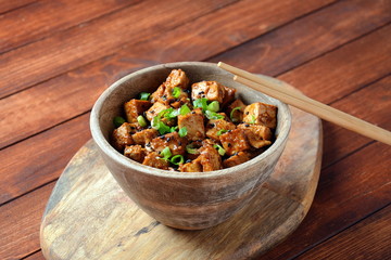Sweet, spicy , crispy and fried Tofu in teriyaki sauce served in a bowl , sesame seeds and rice. Healthy vegan food, gluten-free