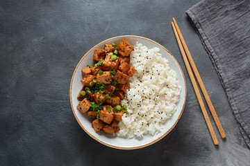 Sweet, spicy , crispy and fried Tofu in teriyaki sauce served in a bowl , sesame seeds and rice. Healthy vegan food, gluten-free