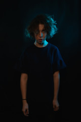 portrait of a girl with curls on a black studio background. in the light of colored lamps. Happy girl