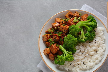 Sweet, spicy , crispy and fried Tofu in teriyaki sauce served in a bowl with broccoli, sesame seeds and rice. Healthy vegan food, gluten-free
