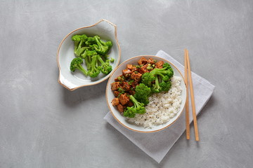 Sweet, spicy , crispy and fried Tofu in teriyaki sauce served in a bowl with broccoli, sesame seeds and rice. Healthy vegan food, gluten-free