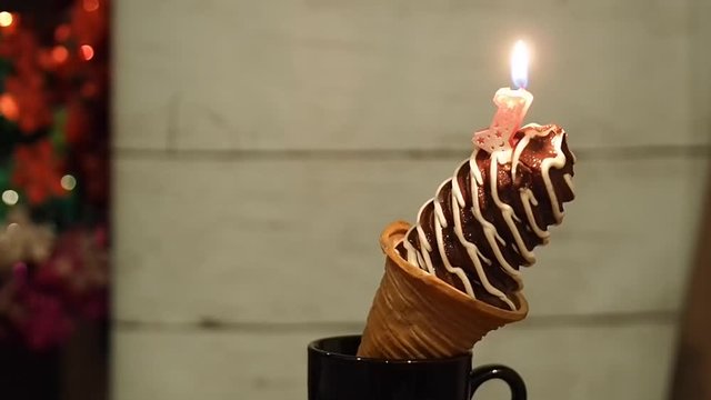 Small chocolate twist with vanilla favor ice cream cone birthday and light number one candle with colorful background 