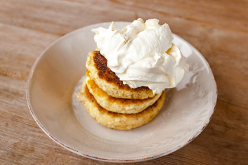 Russian traditional breakfast cottage cheese pancake in plate with sugar powder on wooden background