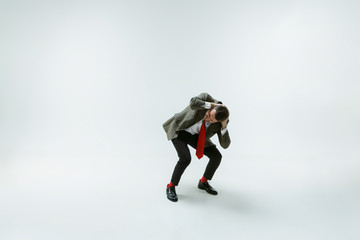 Young caucasian man moving flexible on white studio background. Male model in office attire bending...