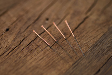 four copper wire acupuncture needles on dark old aok wood
