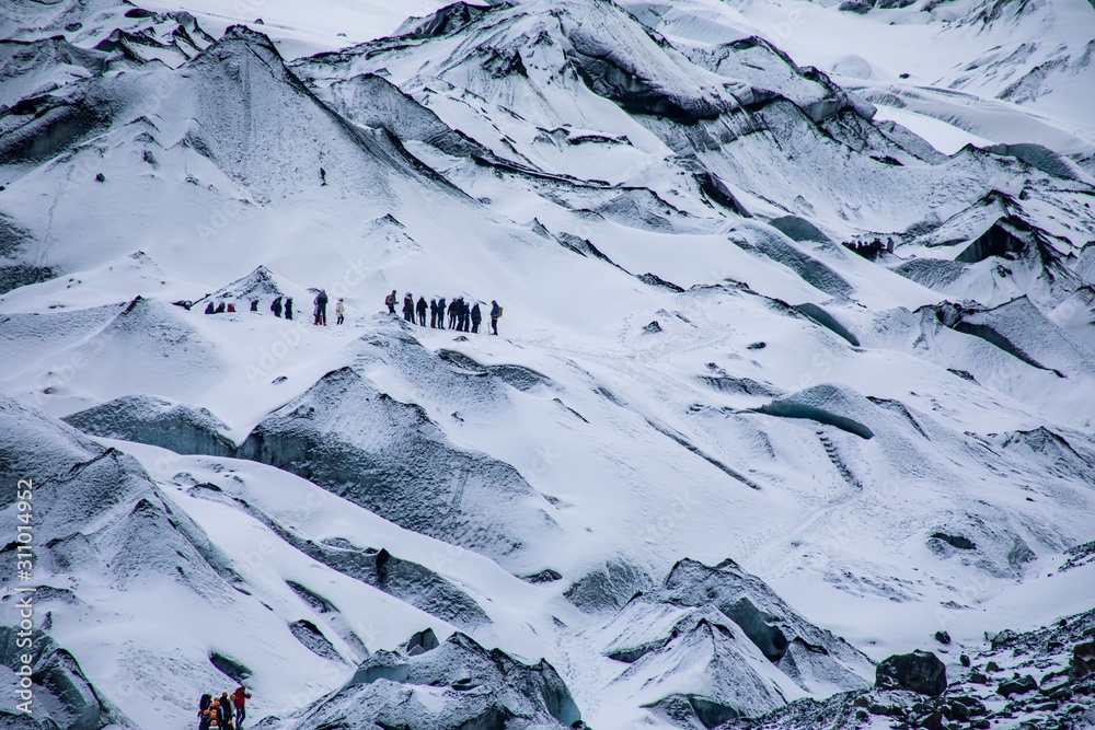 Sticker snowy rugged white mountains with the hiking travelers in wintertime