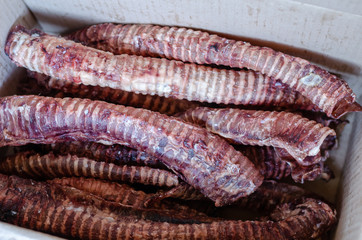 Dried beef trachea king size. Natural treats for dogs. Dried healthy treats for chewing in a cardboard box to be sent by the postal company to the buyer. Selective focus.