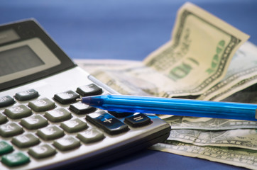 still life of a Notepad, calculator, pen and dollars that lie on a blue background