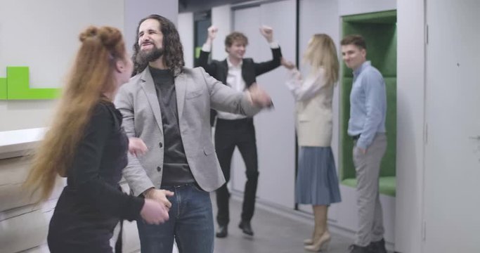 Portrait of group of young office workers throwing papers up and jumping. Multiethnic team celebrating business success. Cinema 4k ProRes HQ.