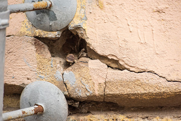 Old stone wall with cracks and metal mount