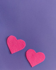 Obraz premium Pink felt hearts with green clothespins on a purple background. St. Valentine's Day and romance concept. Top view, flat lay. Copy space.