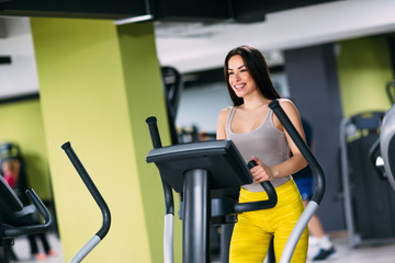 Young fitnes girl exercising on cross trainer machine