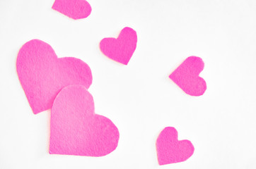 Pink felt hearts on a white background. St. Valentine's Day and romance concept. Top view, flat lay. Copy space.