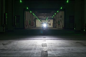 An electric bike with lights on parked in a dim underground passage