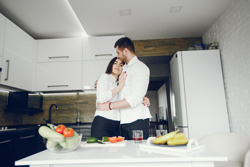 Lovely couple at home in a kithen. Woman and man prepare salad. Woman in a white shirt