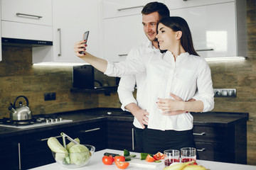 Lovely couple at home in a kithen. Woman and man prepare salad. Woman in a white shirt. Lady with...