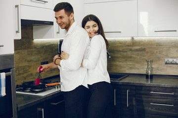 Cute couple on a kitchen. Pretty brunette in a white shirt.