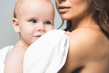 cropped view of naked mother hugging positive baby boy, isolated on grey
