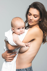 portrait of nude mother holding baby boy, isolated on grey