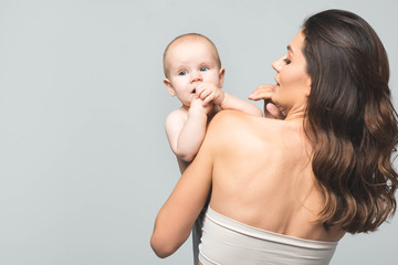 rear view of young mother holding baby boy, isolated on grey
