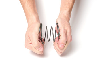 Man with two hands squeezes a spring on a white background.