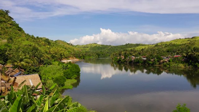 Tropical landscape in sunny weather. Village by the river. Green hills and river. Summer and travel vacation concept. The nature of the Philippine Islands.
