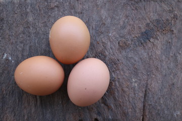  Three eggs on a wooden table being brought to cook