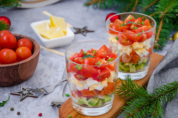 Portion salad with smoked salmon, avocado, egg, cherry tomatoes with cream cheese dressing in a glass.  Holiday salad for Christmas and New Year.