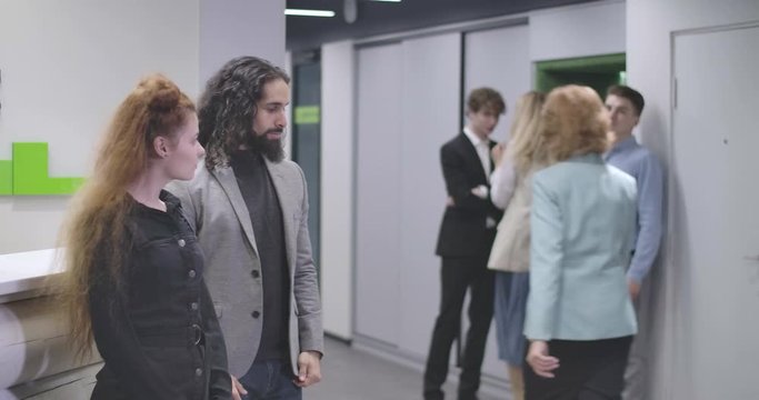 Group of young office workers having fun, stopping while manager coming through, and laughing. Cheerful multiethnic team celebrating business success. Cinema 4k ProRes HQ.
