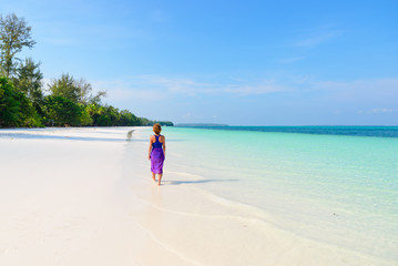 Woman walking on tropical beach. Rear view white sand beach turquoise trasparent water caribbean sea real people. Indonesia Kei Islands Moluccas travel destination.